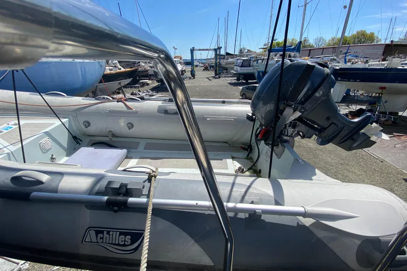 Slide: The Image of Inflatable boat with outboard motor in a marina, surrounded by sailboats. - 38