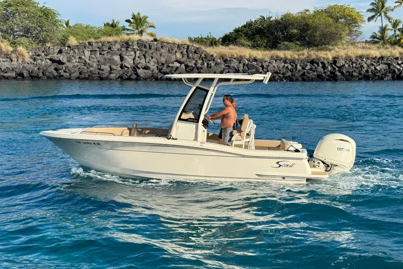 The Image of 2025 Scout 215 XSF boat cruising on blue water near rocky shoreline. - 1