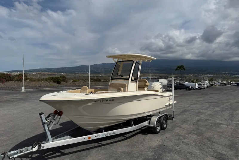 Slide: The Image of 2025 Scout 215 XSF boat on trailer, parked with scenic mountain backdrop. - 12