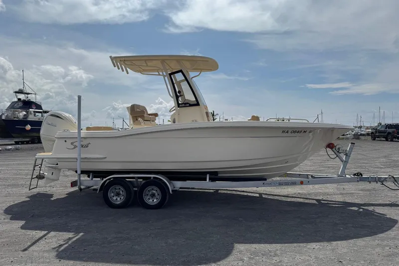 Slide: The Image of 2025 Scout 215 XSF boat on trailer, parked outdoors under a cloudy sky. - 6