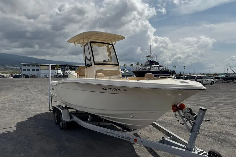 Slide: The Image of 2025 Scout 215 XSF boat on trailer in marina parking lot under cloudy sky. - 7