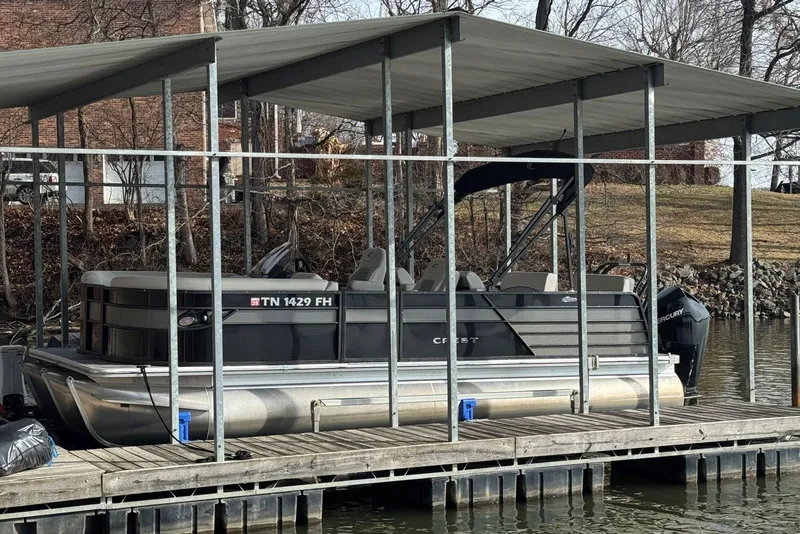 The Image of 2022 Crest Classic Platinum 220 SLRC pontoon boat docked under a covered structure. - 0