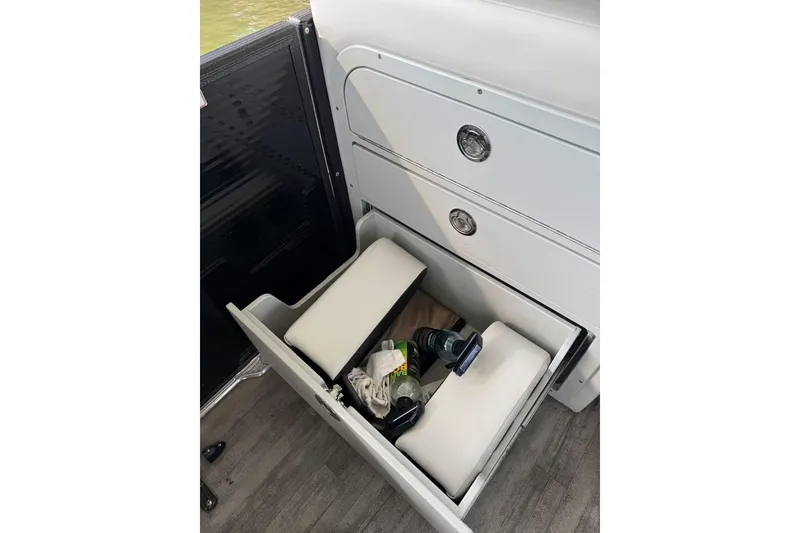 Slide: The Image of Open storage drawer in 2022 Crest Classic Platinum 220 SLRC boat, containing cushions and bottles. - 28