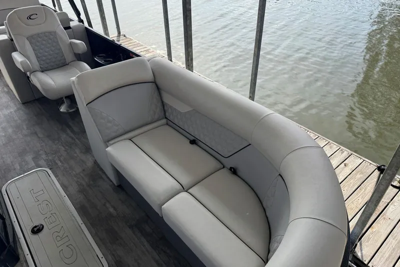 Slide: The Image of 2022 Crest Classic Platinum 220 SLRC pontoon boat interior with plush seating by the water. - 6