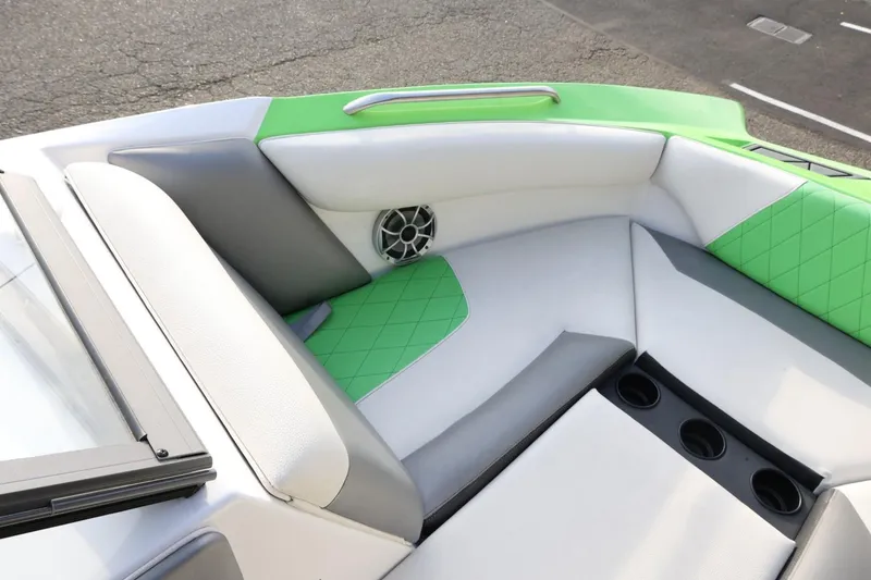 Slide: The Image of 2016 Tigé R22 boat interior with green and gray seating, cup holders, and speaker. - 16