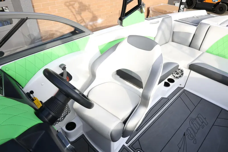 Slide: The Image of 2016 Tigé R22 boat interior with green and gray seating, steering wheel, and speaker. - 19