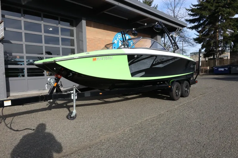 Slide: The Image of 2016 Tigé R22 boat on trailer, lime green and black, parked outside a garage. - 3