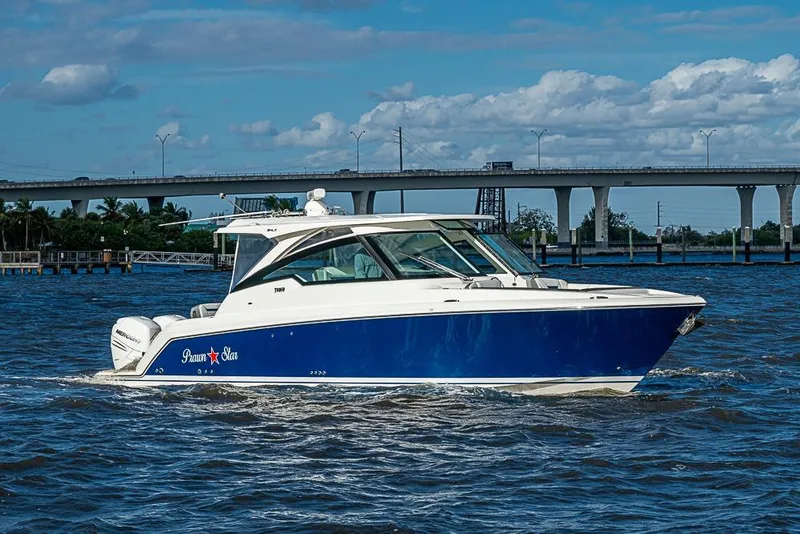 The Image of 2022 Tiara Yachts 34 LX cruising on a sunny day near a bridge. - 0
