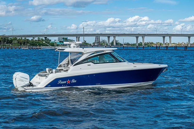 Slide: The Image of 2022 Tiara Yachts 34 LX cruising on a sunny day with a bridge in the background. - 10