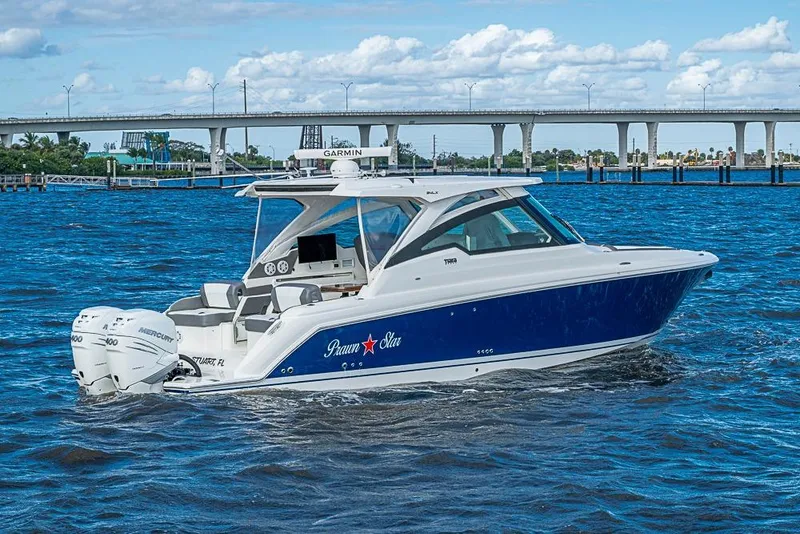 Slide: The Image of 2022 Tiara Yachts 34 LX cruising on blue waters near a bridge. - 11