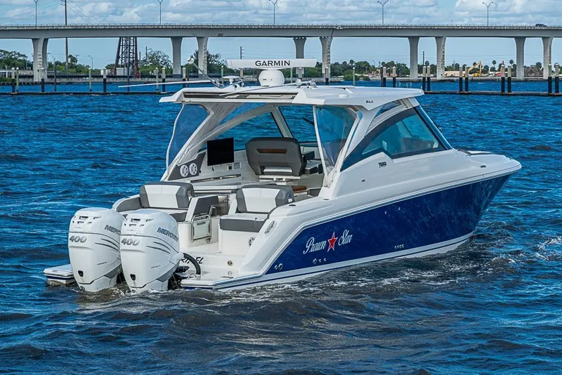 Slide: The Image of 2022 Tiara Yachts 34 LX boat cruising on blue water near a bridge. - 12