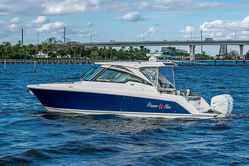 Slide: The Image of 2022 Tiara Yachts 34 LX cruising on a sunny day near a bridge. - 17