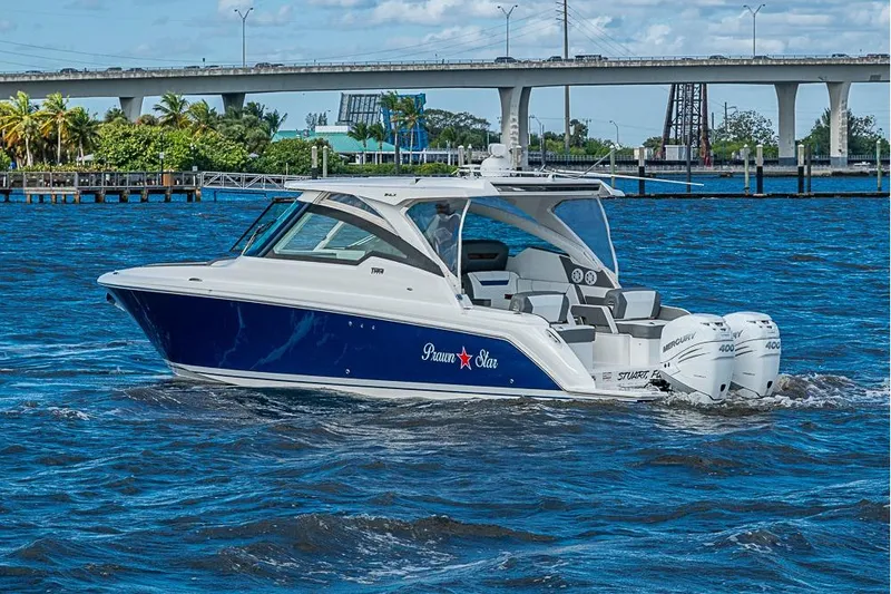 Slide: The Image of 2022 Tiara Yachts 34 LX cruising on a sunny day near a bridge. - 2