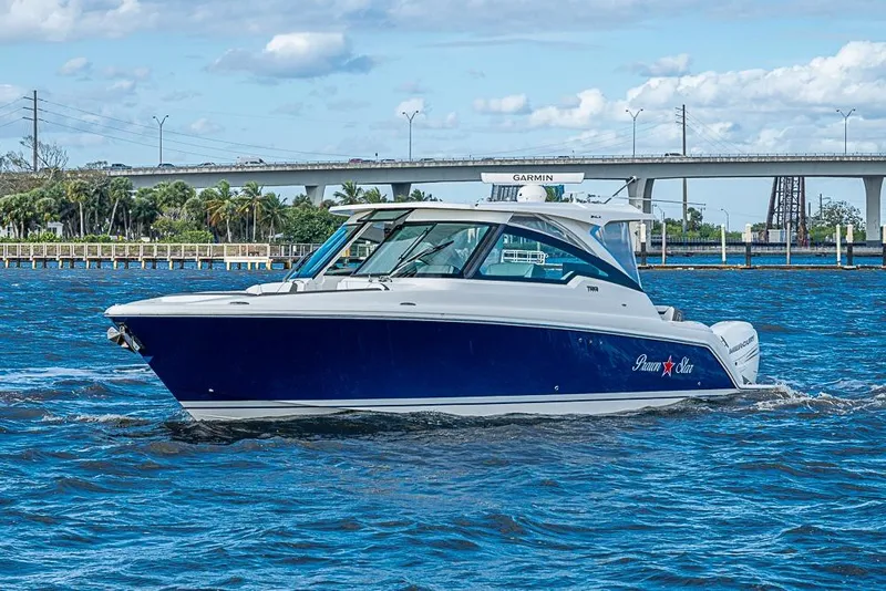Slide: The Image of 2022 Tiara Yachts 34 LX cruising on blue water near a bridge. - 5