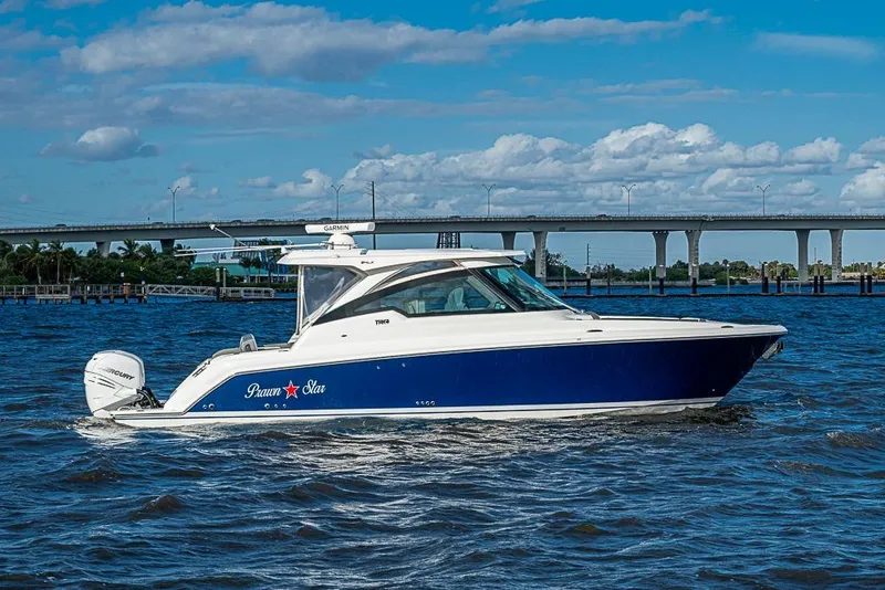 Slide: The Image of 2022 Tiara Yachts 34 LX cruising on a sunny day with a bridge in the background. - 8