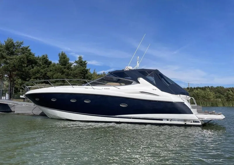 Slide: The Image of 2003 Sunseeker Portofino 46 yacht docked on a sunny day, surrounded by trees. - 1