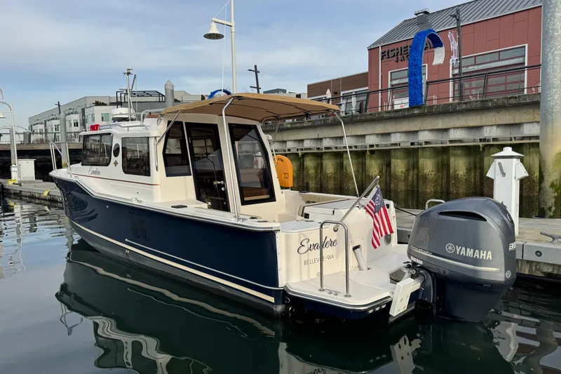 Slide: The Image of 2021 Ranger Tugs R-27 boat docked with Yamaha engine, American flag displayed. - 1