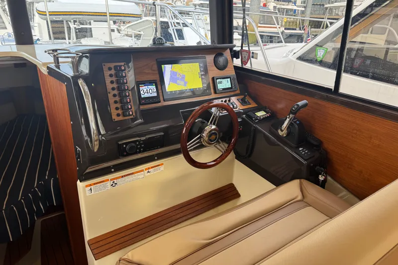 Slide: The Image of 2021 Ranger Tugs R-27 helm with navigation screens and controls in a marina setting. - 11