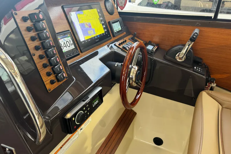 Slide: The Image of 2021 Ranger Tugs R-27 helm with navigation controls, wooden steering wheel, and modern electronics. - 12
