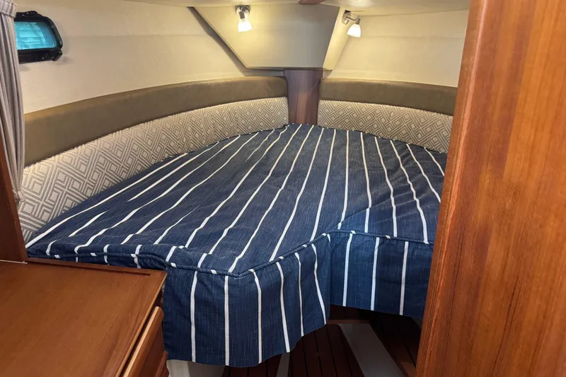 Slide: The Image of Cozy cabin interior of 2021 Ranger Tugs R-27 with striped bedding and wood accents. - 15