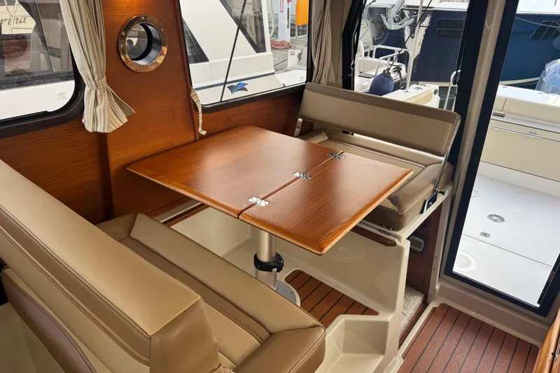 Slide: The Image of Interior of 2021 Ranger Tugs R-27 with wooden table and beige seating. - 18