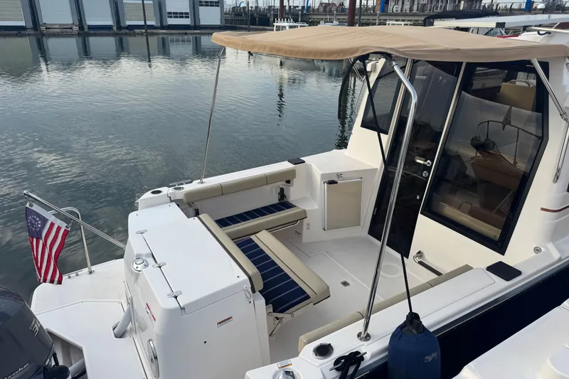 Slide: The Image of 2021 Ranger Tugs R-27 boat with seating area and American flag at marina. - 3