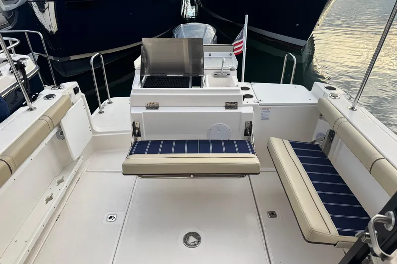 Slide: The Image of 2021 Ranger Tugs R-27 boat deck with seating and grill, docked at marina. - 4