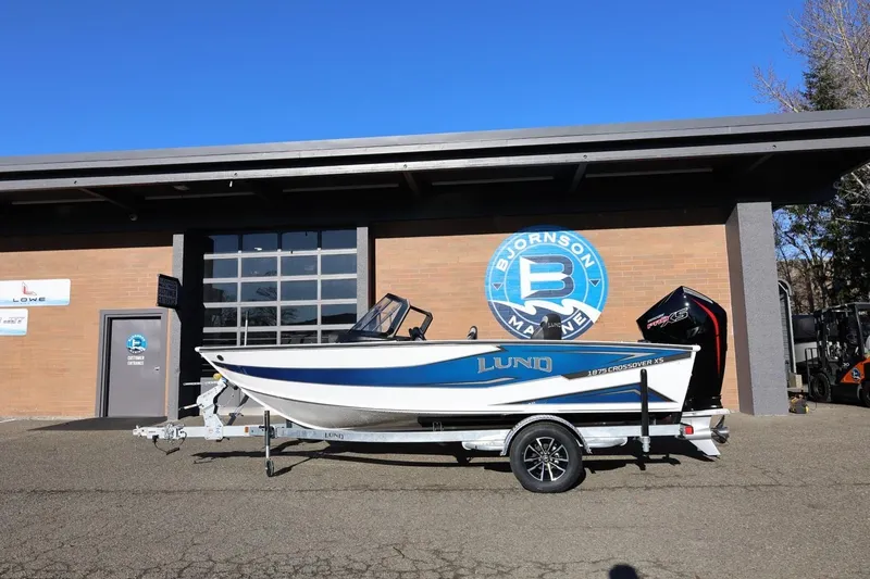The Image of 2026 Lund 1875 Crossover XS boat on trailer outside Bjornson Marine building. - 1