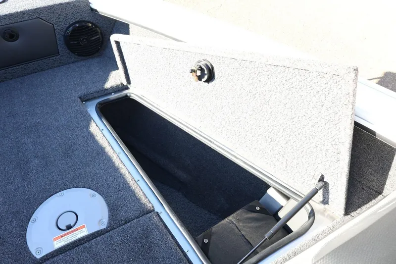 Slide: The Image of 2026 Lund 1875 Crossover XS boat storage compartment with open hatch and carpeted interior. - 19