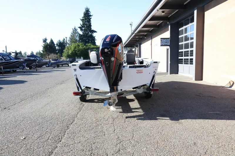 Slide: The Image of 2026 Lund 1875 Crossover XS boat with outboard motor in a dealership lot. - 7