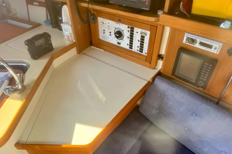 Slide: The Image of Navigation station inside a 1995 Catalina 320 sailboat with control panels and seating. - 10