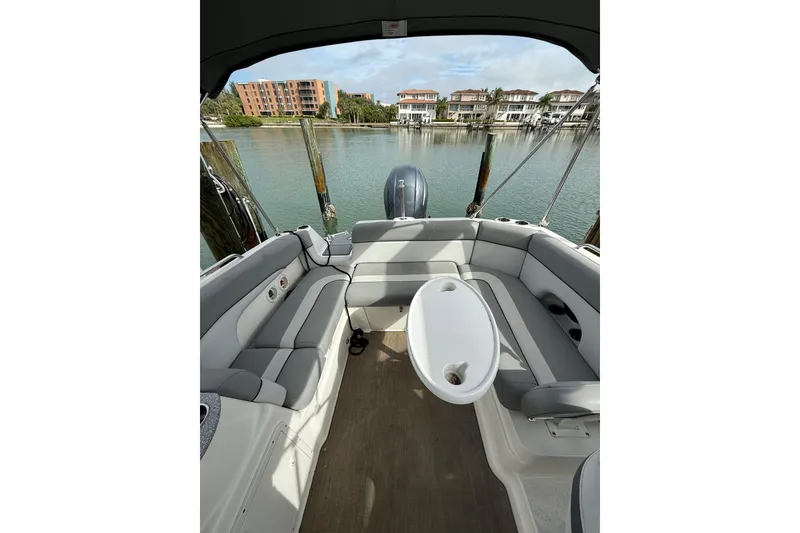 Slide: The Image of Interior view of 2022 NauticStar 243 DC boat with seating and table, docked by waterfront. - 7
