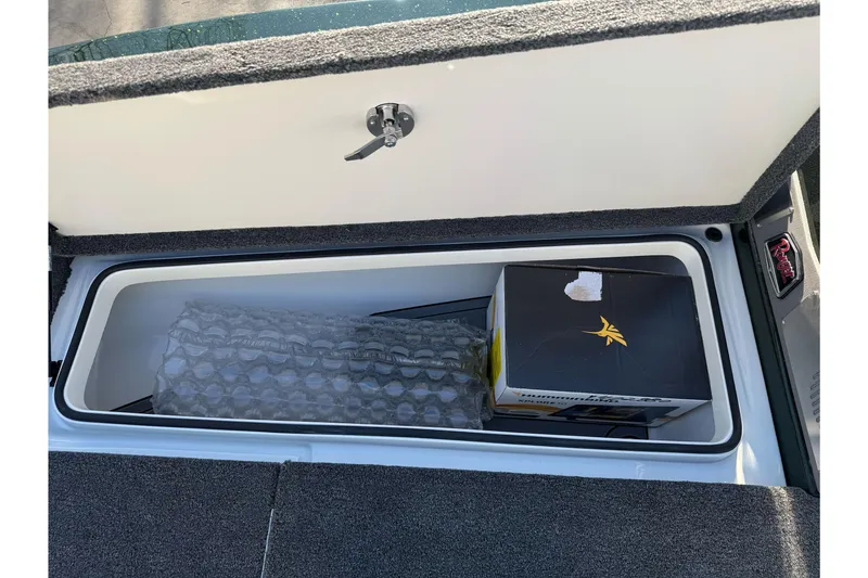 Slide: The Image of Storage compartment in 2026 Ranger 620xFS Pro boat, containing a box and bubble wrap. - 27