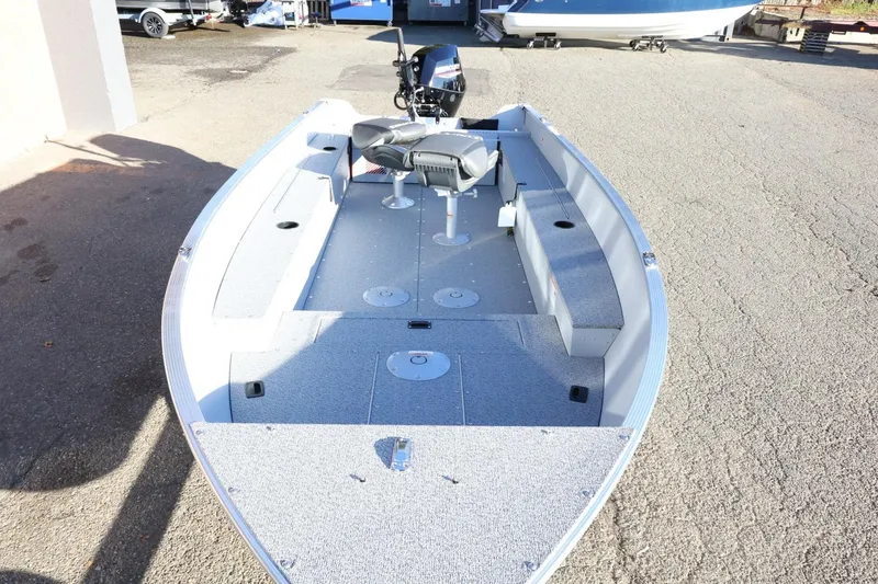 Slide: The Image of 2026 Lund 1600 Fury Tiller boat with seating and motor, parked on pavement. - 10