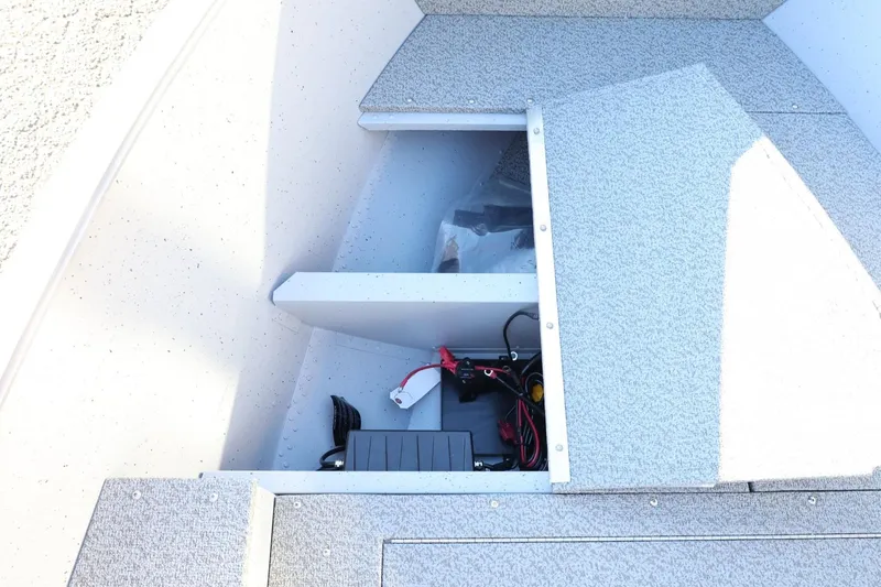 Slide: The Image of 2026 Lund 1600 Fury Tiller boat storage compartment with wiring and battery setup. - 14