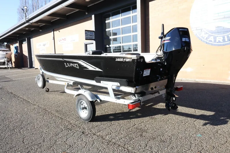 Slide: The Image of 2026 Lund 1600 Fury Tiller boat on trailer, parked outside a building. - 8