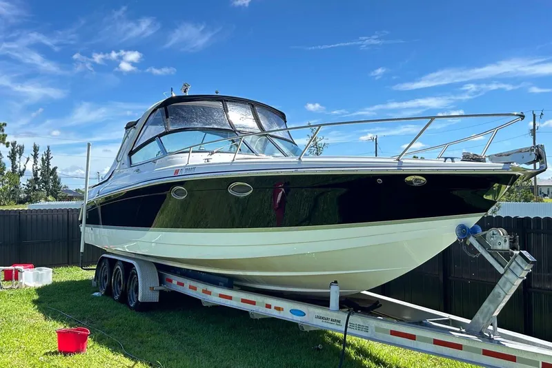 The Image of 2006 Formula 330 Sun Sport boat on trailer, parked on grass under clear blue sky. - 1