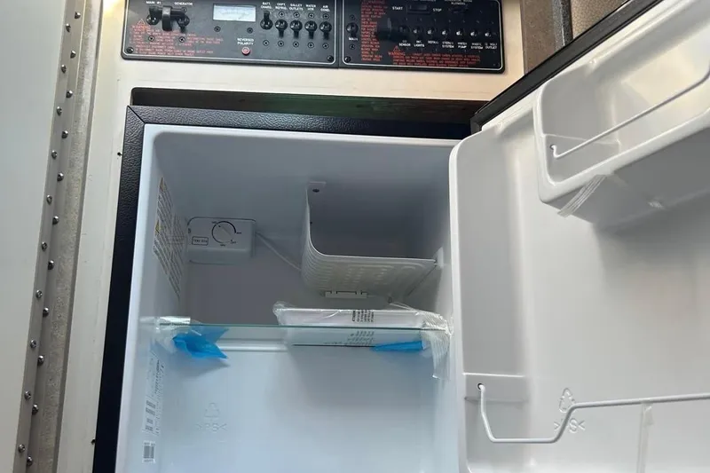 Slide: The Image of Open refrigerator inside a 2006 Formula 330 Sun Sport boat, showing control panel above. - 10