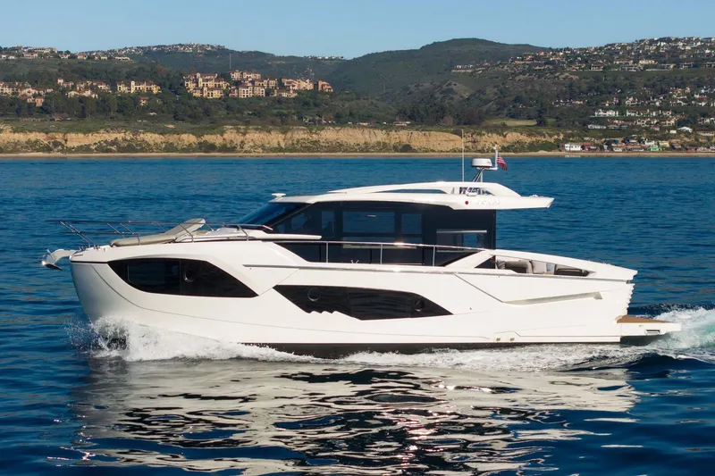 The Image of 2026 Absolute 48 Coupe yacht cruising on blue ocean near scenic coastline. - 0