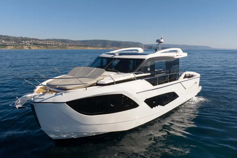 Slide: The Image of 2026 Absolute 48 Coupe yacht cruising on open water under clear skies. - 4