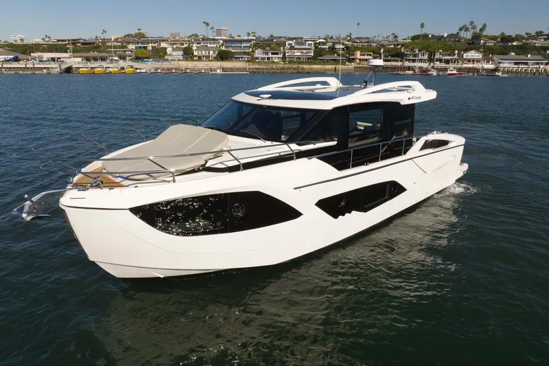 Slide: The Image of 2026 Absolute 48 Coupe yacht cruising in a scenic harbor setting. - 9
