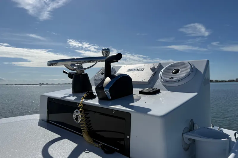 Slide: The Image of 2024 East Cape 25 Hybrid boat console with steering wheel and controls on a sunny day. - 27