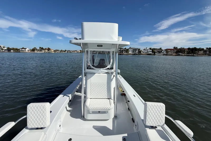 Slide: The Image of 2024 East Cape 25 Hybrid boat on calm water, clear sky, coastal homes in background. - 32