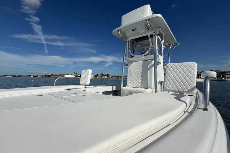 Slide: The Image of 2024 East Cape 25 Hybrid boat with white seating on calm water under blue sky. - 34