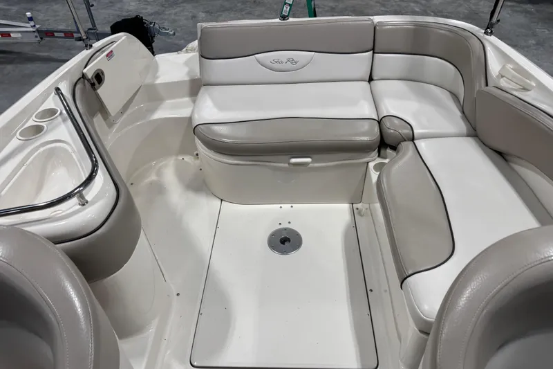 Slide: The Image of 2004 Sea Ray 240 Sundeck interior with beige seating and cup holders. - 8