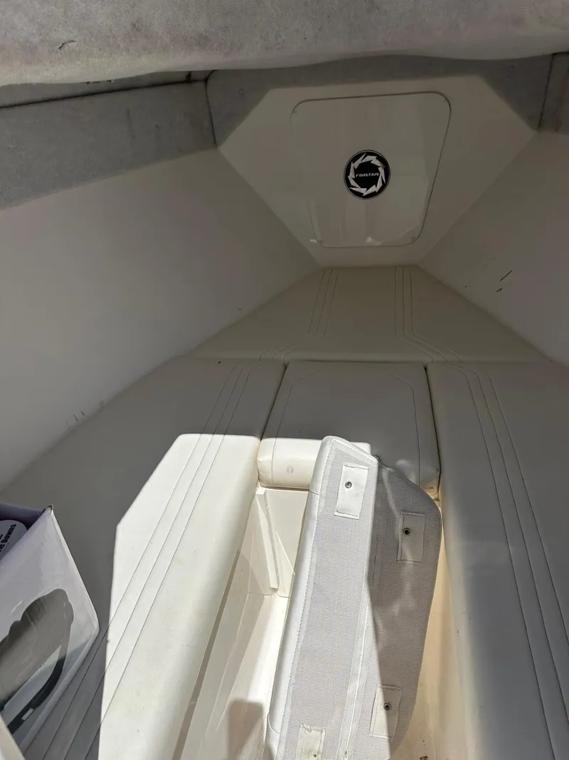 Slide: The Image of 2004 Fountain 31 Tournament Edition boat interior with white seating and storage compartment. - 15