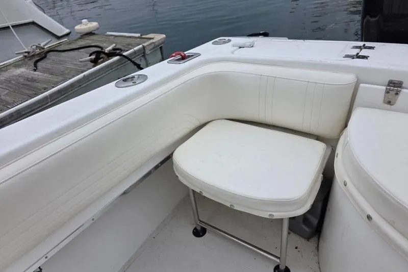 Slide: The Image of 2004 Fountain 31 Tournament Edition boat interior with white seating near dock. - 26