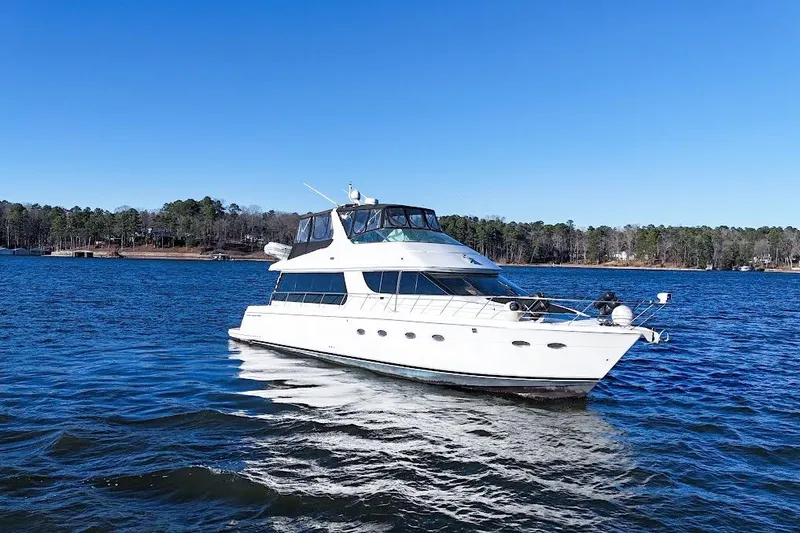 Slide: The Image of 2001 Carver 570 Voyager Pilothouse yacht cruising on a serene lake under clear blue skies. - 12