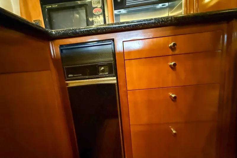 Slide: The Image of 2001 Carver 570 Voyager Pilothouse kitchen with wooden cabinets and built-in appliances. - 23