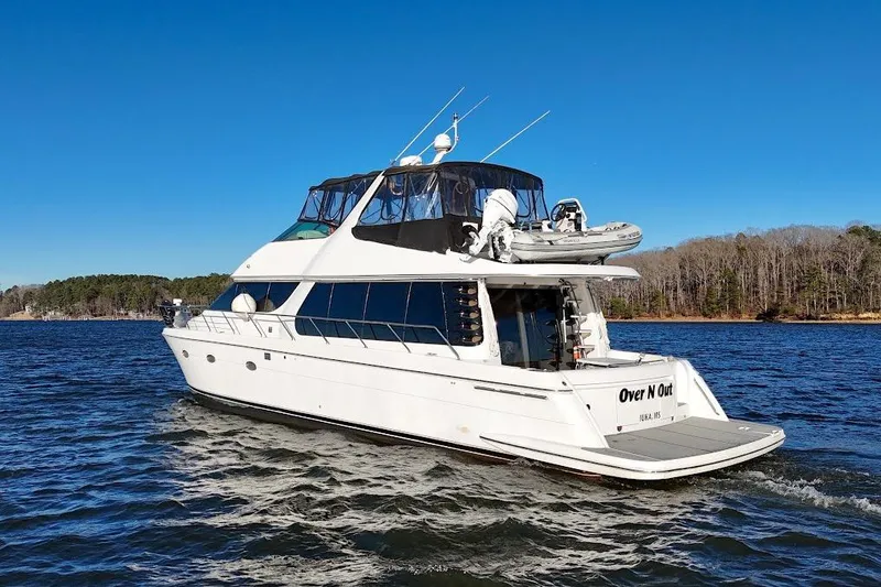 Slide: The Image of 2001 Carver 570 Voyager Pilothouse yacht cruising on a sunny day, surrounded by calm waters. - 4